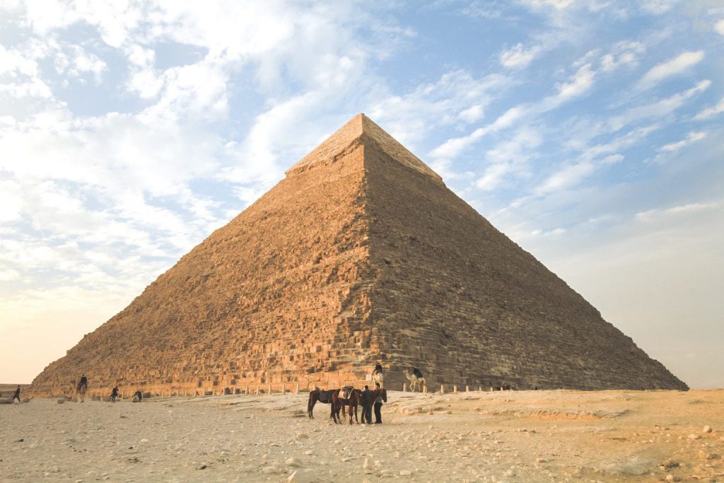 A ground view picture of a pyramid in Egypt with people at the base