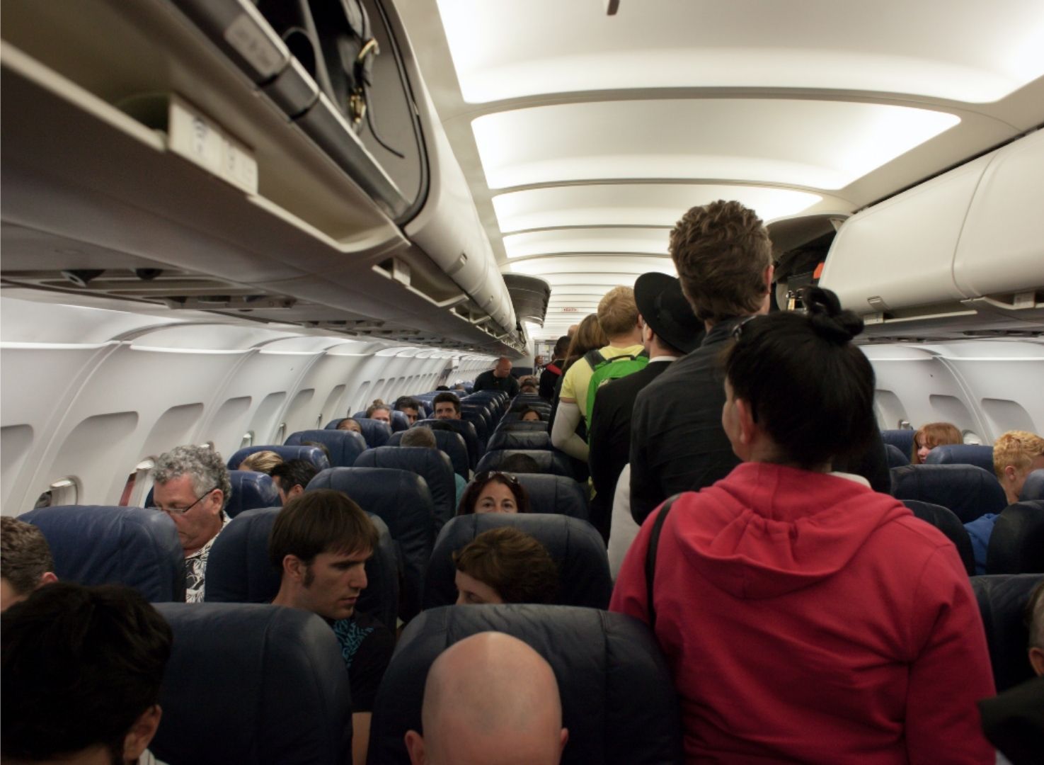 People going to their seats in an airplane preparing for departure